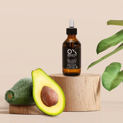 Avocado cut open with a bottle of avocado oil
